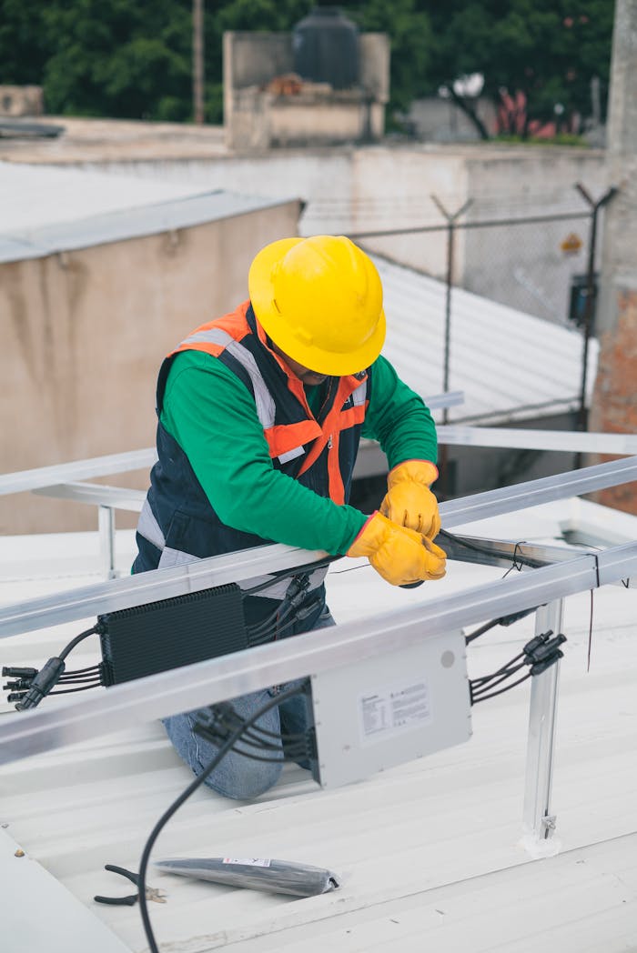 Home Electrician with PPE working on rooftop solar panel installation, focusing on safety.